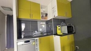 Uma cozinha compacta com armários amarelos, um micro-ondas e uma máquina de lavar louça.