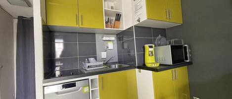 A compact kitchen with yellow cabinets, a microwave, and a dishwasher.