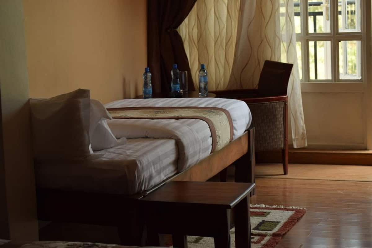A bedroom with a bed, a chair, a table, and a window with curtains.