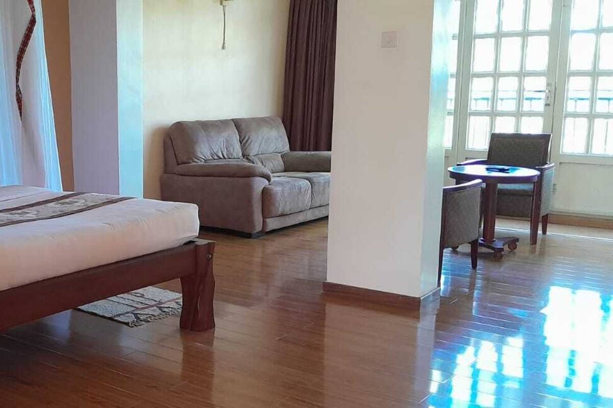 A bedroom with a bed, a sofa, a chair, and a small table.