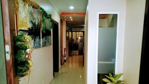 A hallway with a potted plant, a framed picture, and a door with a golden tinsel decoration. - The Lodge by Kabachi (Lagos)