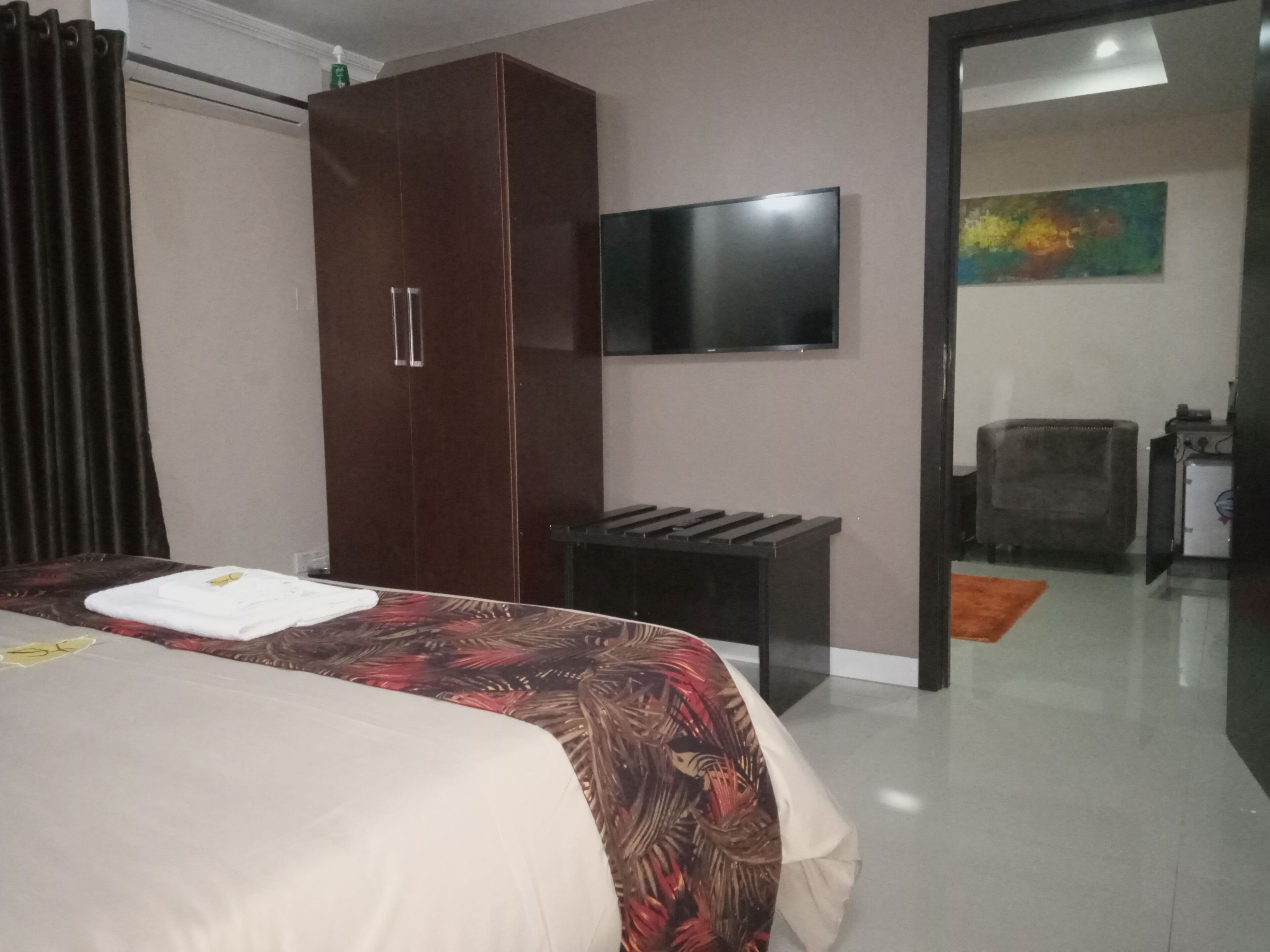 Ein Hotelzimmer mit Bett, Kleiderschrank, Fernseher und einer kleinen Sitzecke.