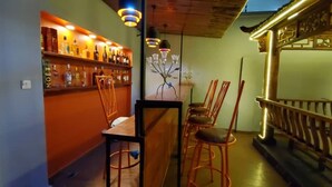 A bar area with a wooden counter, multiple bottles, and a seating arrangement with chairs. - The Lodge by Kabachi (Lagos)