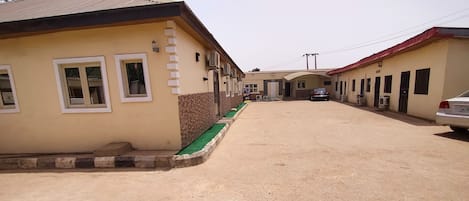 A residential street with houses, a covered area, and parked cars.