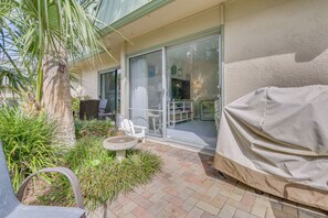 Une terrasse avec un barbecue couvert, une chaise et une petite table.