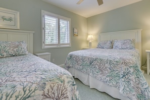 A bedroom with two beds, a window with blinds, a bedside table with a lamp, and a ceiling fan. - Walk to Beach! Hilton Head Island Escape w/ Pool (Hilton Head Island)