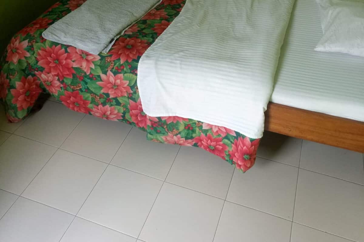 A small, single-bed room with a floral bedspread and green walls.