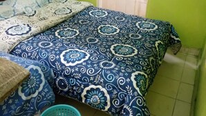 Un dormitorio con cama, cabecero de madera, pared verde y ventana con cortina.