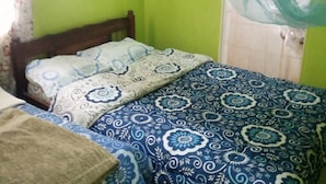 Un dormitorio con dos camas, cada una con ropa de cama estampada, cabeceros de madera y mosquiteros.