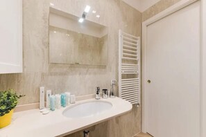 Une salle de bain avec un grand miroir, un lavabo et un porte-serviettes.