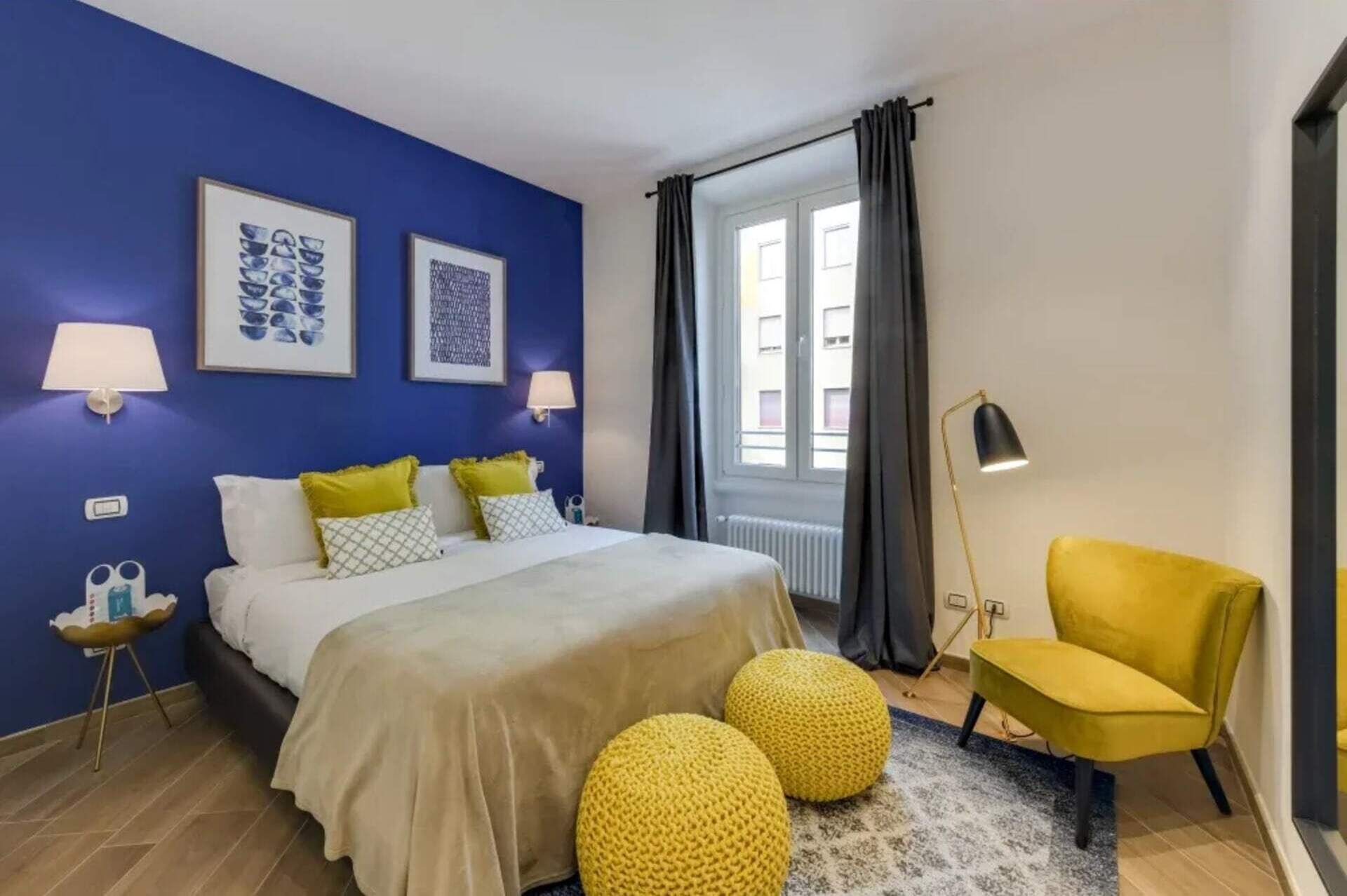 Une chambre à coucher avec un lit, deux lampes de chevet, une chaise et une fenêtre avec des rideaux.