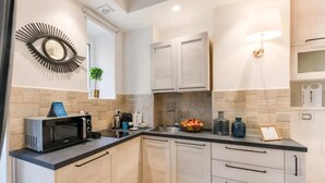 Una cocina moderna con microondas, cafetera y frutero sobre la encimera.