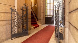 Eine prächtige Treppe mit rotem Teppich, der zu einer Tür mit aufwendiger Metallverzierung führt.