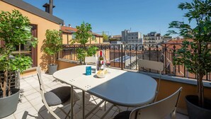 En balkon med et bord, stole og plantekrukker.