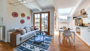 En moderne stue med sofa, sofabord og udsigt over byen gennem store vinduer.