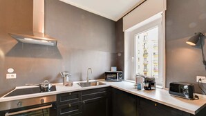 Una cucina compatta con fornello, forno, lavello e una finestra che dà su un edificio.