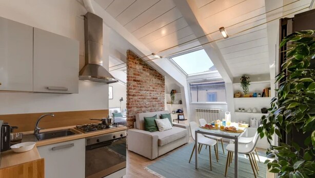 A modern kitchen with a brick accent wall, a dining area with a table and chairs, and a cozy seating area with a sofa. - Sweett | Sempione I - One Bedroom Apartment, Sleeps 2 (Milano)