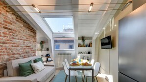 A compact kitchen with a dining area, a sofa, and a TV. - Sweett | Sempione I - One Bedroom Apartment, Sleeps 2 (Milano)