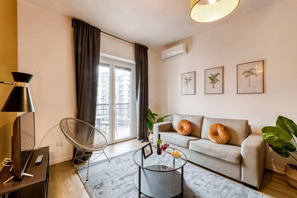 A modern living room with a sofa, a round coffee table, a chair, and a TV.