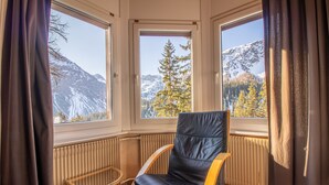 A room with a large window, a black leather chair, a wooden chair, and a bed. - Miraflor Carmen (Arosa)