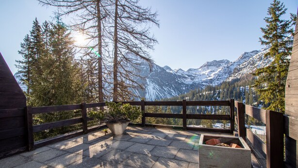A wooden deck with stone tiles, a wooden fence, and a view of snow-capped mountains. - Miraflor Carmen (Arosa)