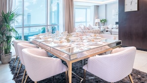 A modern dining area with a glass table, white chairs, and a city view.