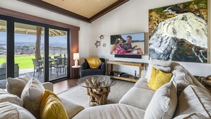 A living room with a large window, a sofa, a coffee table, and a TV.