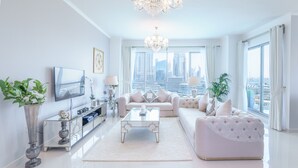 A modern living room with a large TV, a sofa, a coffee table, and a view of the cityscape.