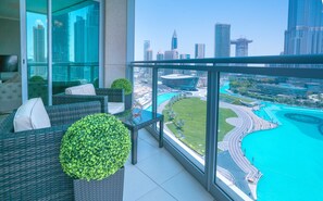 Ein Balkon mit Rattanmöbeln, einem Glastisch und Blick auf Stadt und Wasser.
