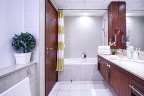 Ein modernes Badezimmer mit einer Badewanne, einem großen Spiegel und einer Topfpflanze.