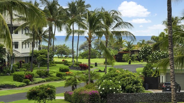 A tropical resort with palm trees, a well-maintained lawn, and a view of the ocean. - Vista Waikoloa B-206 2 Bedroom Condo by RedAwning (Waikoloa)