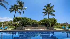 A swimming pool with clear blue water, surrounded by palm trees and lounge chairs. - Vista Waikoloa B-206 2 Bedroom Condo by RedAwning (Waikoloa)