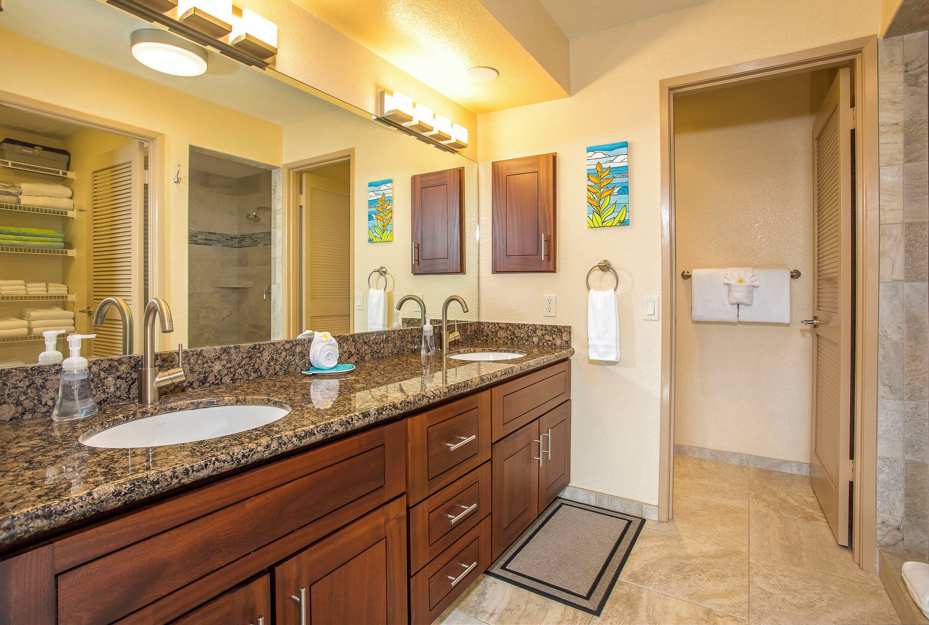 A bathroom with two sinks, wooden cabinets, a large mirror, and a shower area.