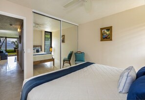 Un dormitorio con cama, una silla, un cuadro y vistas a un balcón.
