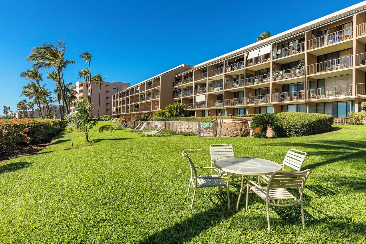 A hotel with multiple balconies, a well-maintained lawn, and a clear blue sky.