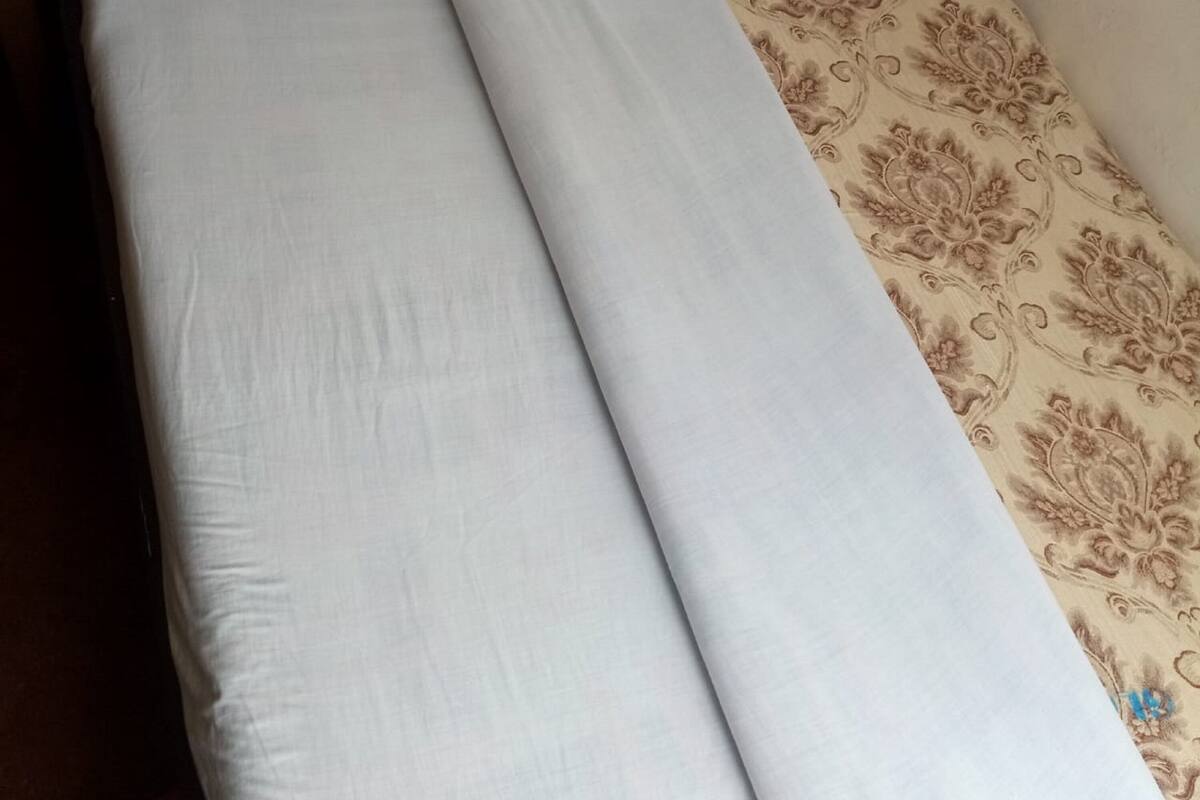 Un lit avec du linge de lit blanc et une couvre-lit à motifs.