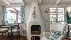 A cozy room with a fireplace, a dining table with chairs, and a comfortable armchair. - Magnificent Depandance with Pool in Villa 900 mt from the beach (San Felice Circeo)