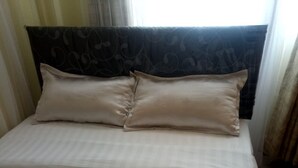 A bed with beige bedding and a dark headboard. - Hotel Joska (Nakuru)
