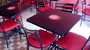 A restaurant interior with red chairs and black tables, featuring a tiled floor and a pink wall. - Hotel Joska (Nakuru)