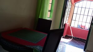 A dining area with a table and chairs, a green curtain, and a red door leading outside.