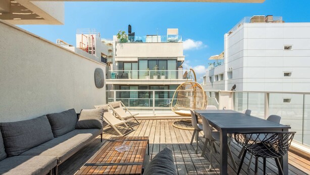 Eine Dachterrasse mit Holzdeck, einer Couch, einem Tisch und einem Stuhl.