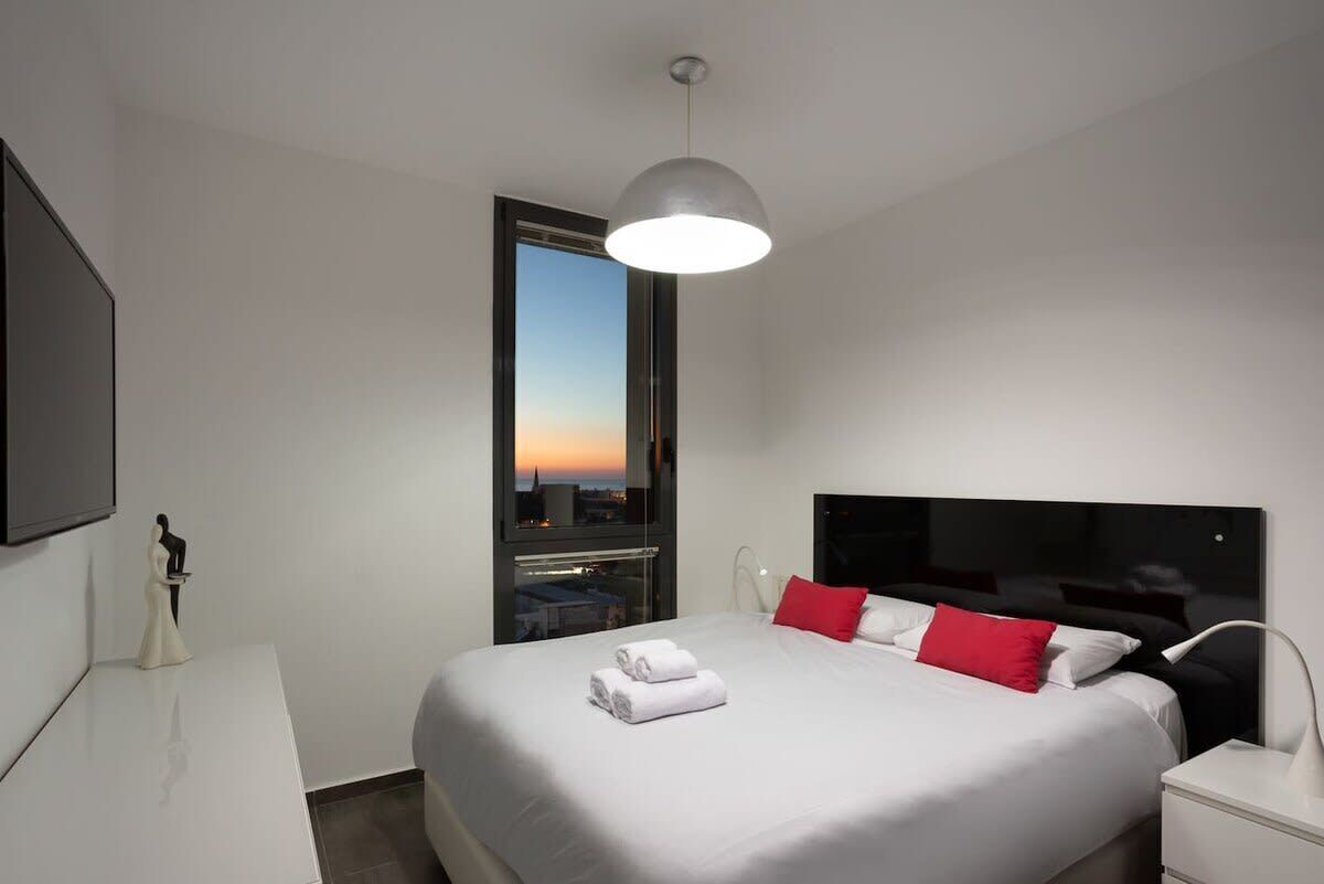 Ein modernes Hotelzimmer mit einem großen Bett, einem Flachbildfernseher, einem Schreibtisch und einem Fenster mit Blick auf die Stadt.