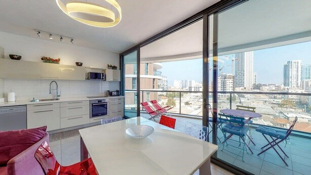 Una cucina moderna con una grande finestra, una zona pranzo con tavolo e sedie, e vista sulla città.