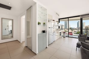 A modern kitchen with a large window, a dining area with a sofa, and a view of the cityscape. - Brigth 3BR in Florentin's Complex by HolyGuest (Tel Aviv-Yafo)