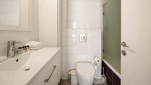 A modern bathroom with a white sink, toilet, and shower area.