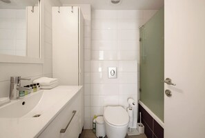 Casa de banho moderna com lavatório branco, sanita e zona de duche.