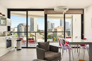 A modern apartment with a kitchen, dining area, and large windows offering city views. - Brigth 3BR in Florentin's Complex by HolyGuest (Tel Aviv-Yafo)