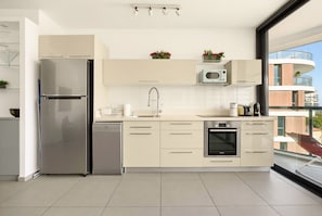Una cocina moderna con lavavajillas integrado, refrigerador de acero inoxidable, microondas y horno.
