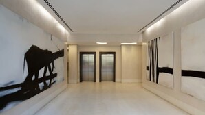 Un corridoio moderno con due ascensori, arredamento minimalista e una palette colori pulita e bianca.