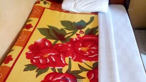 Una cama con una colcha estampada con motivos florales y sábanas blancas.